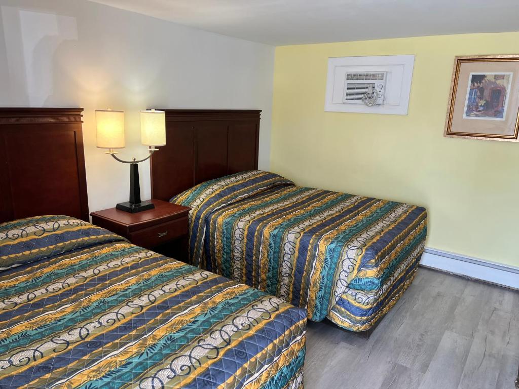 een hotelkamer met 2 bedden en een lamp op een tafel bij Budget Inn Motel Suites Somers Point in Somers Point