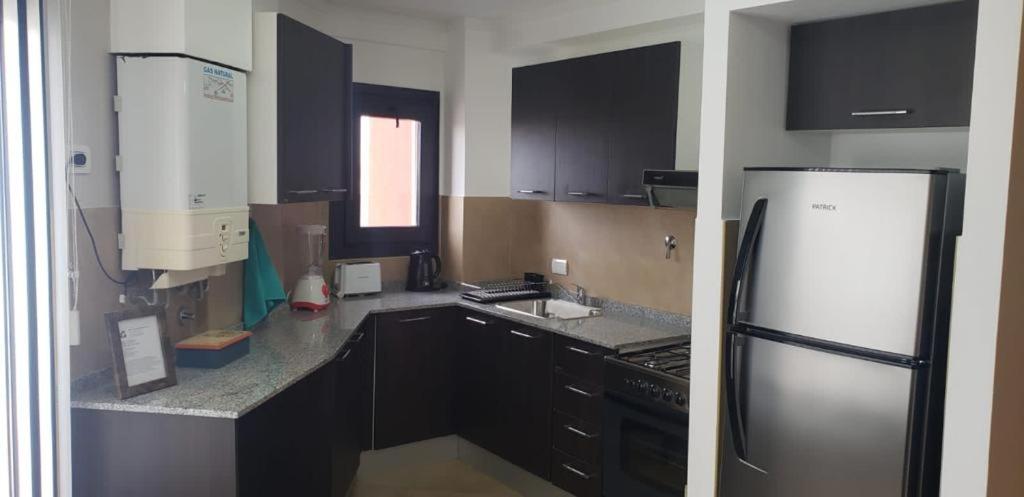uma cozinha com armários pretos e um frigorífico de aço inoxidável em Plaza Temporary Apartments em Rio Grande