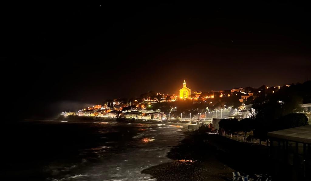 a view of a city at night with a clock tower at Luxury Tugurio in Arma di Taggia