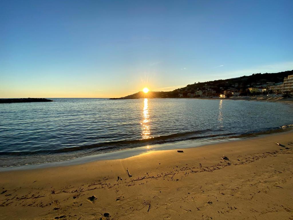 a beach with the sun setting over the water at Luxury Tugurio in Arma di Taggia