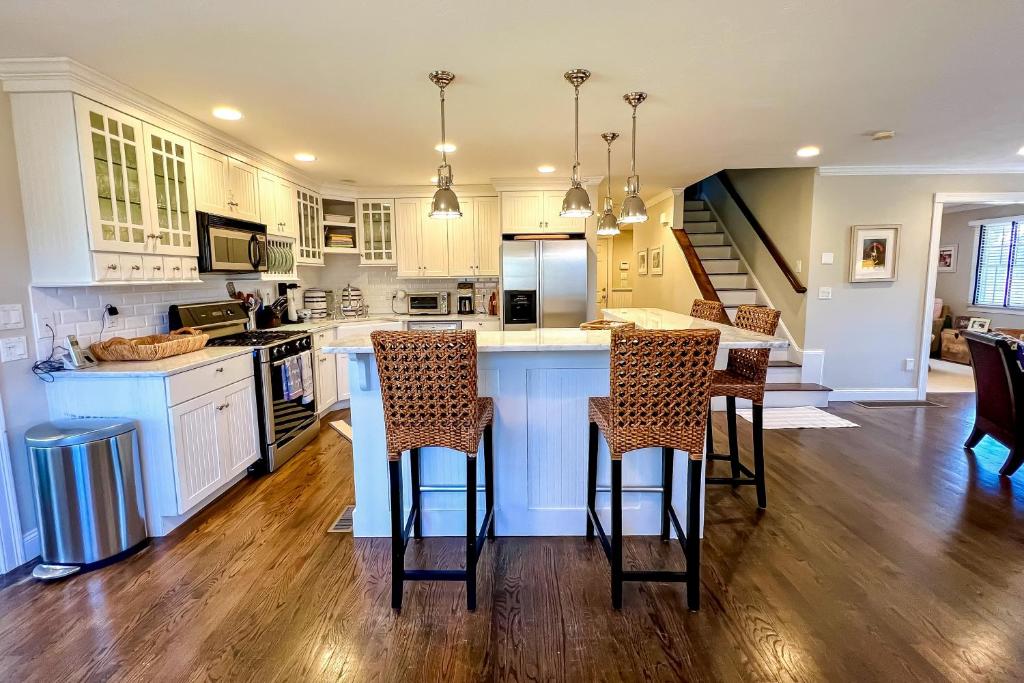 a kitchen with white cabinets and a island with bar stools at Cotuit Mannor in Cotuit