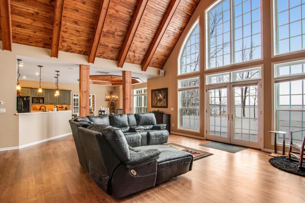 sala de estar con muebles de cuero y ventanas grandes. en North Twin Lake House, en Phelps
