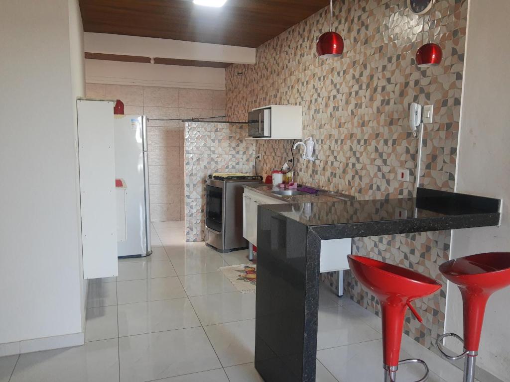 uma cozinha com um balcão preto e bancos vermelhos em Apartamento com suíte, localizado na Avenida Silvio Silva, n 33, bairro Hernani Sa, Ilhéus - Ba, sem garagem em Ilhéus
