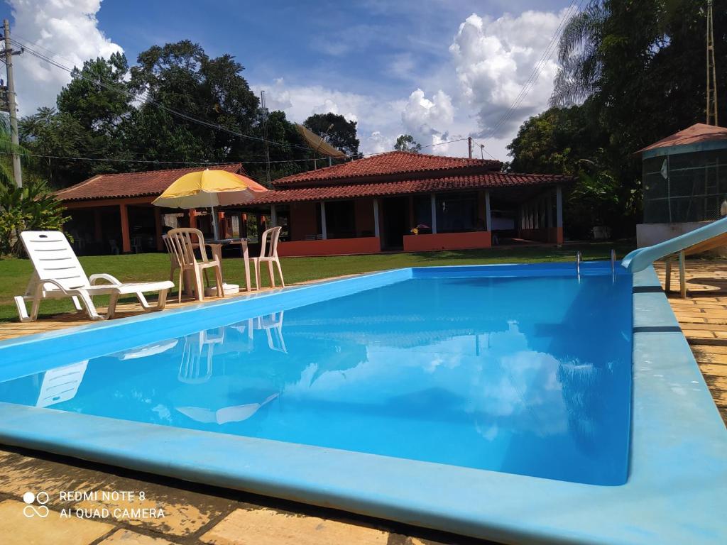 a blue swimming pool with two chairs and a house at chácara solar das águas in Socorro