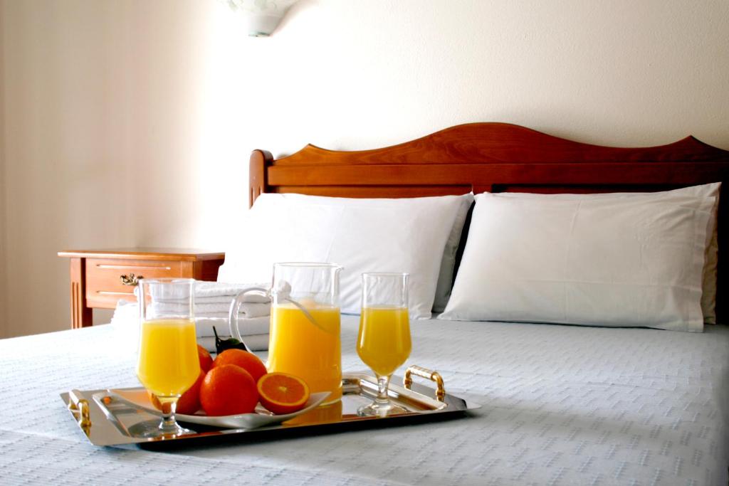 bandeja con 2 vasos de zumo de naranja y fruta en una cama en Zouzoulas Filoxenia - Koralia Apartments, en Milina