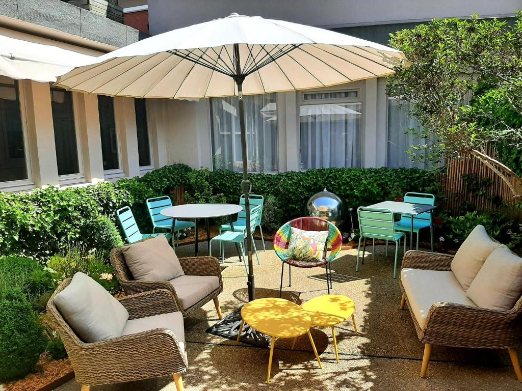 een patio met stoelen en een tafel met een parasol bij Cit'Hotel Grand Hotel L'Etape in Saint-Flour