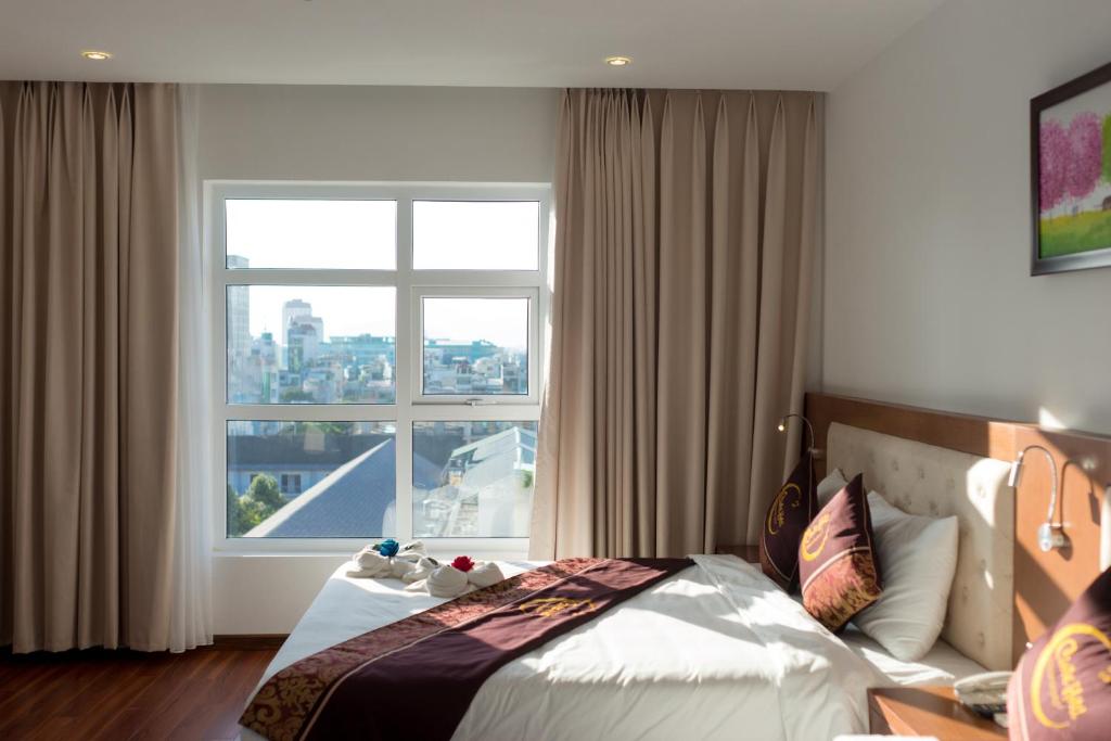 a bedroom with a bed and a large window at Centre Hotel in Da Nang