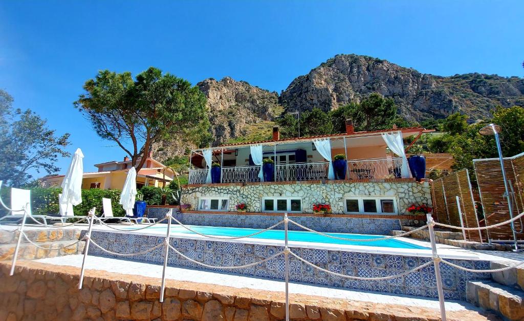 a house with a swimming pool in front of a mountain at VFH Villa Flavia Eco B&B - 50 metri dal mare in Santa Flavia