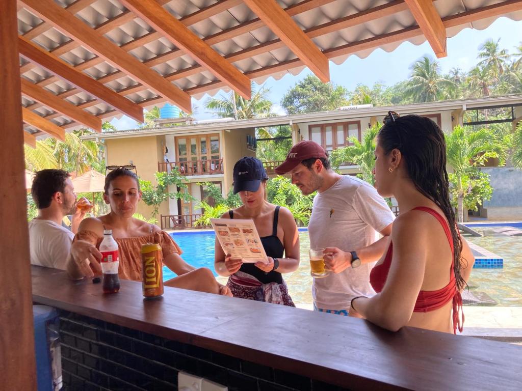 a group of people standing around a bar at Handagedara Resort & Spa in Mirissa