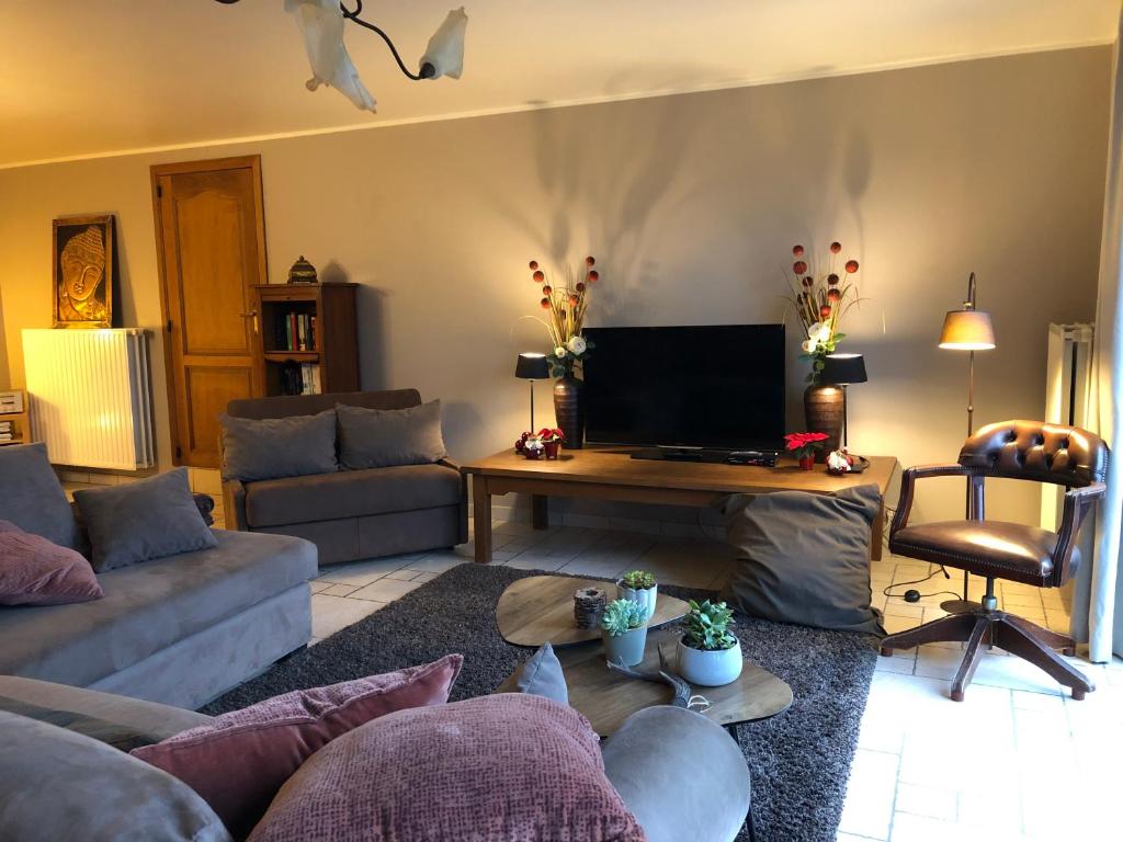 ein Wohnzimmer mit einem Sofa und einem Tisch in der Unterkunft Au Coeur des Collines, Charmette in Ellezelles