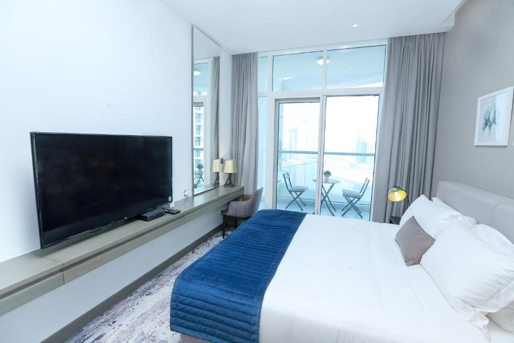 um quarto de hotel com uma cama grande e uma televisão de ecrã plano em DAMAC MAISON PRIVE em Dubai