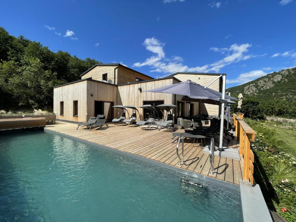 una casa con terrazza in legno e piscina di Le Volcan des Sens, chambres d'hotes de luxe et SPA a Torsiac