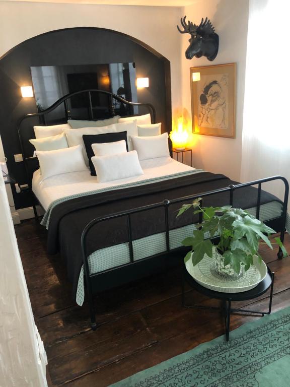 una camera da letto con un grande letto nero con cuscini bianchi di Quai 17 Maison d'hôtes a Strasburgo