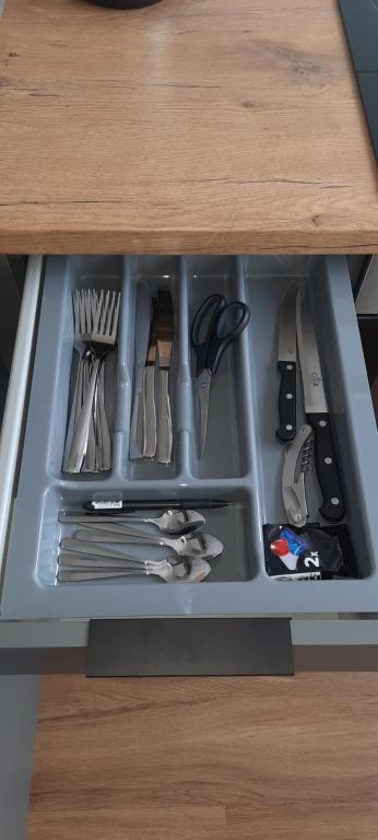 a drawer in a cabinet filled with utensils at Teodora B. Apartament in Liepāja