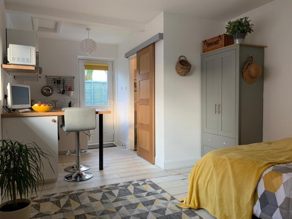 a bedroom with a bed and a desk and a kitchen at The Beehive - Self Contained Studio by The Sea in Exmouth