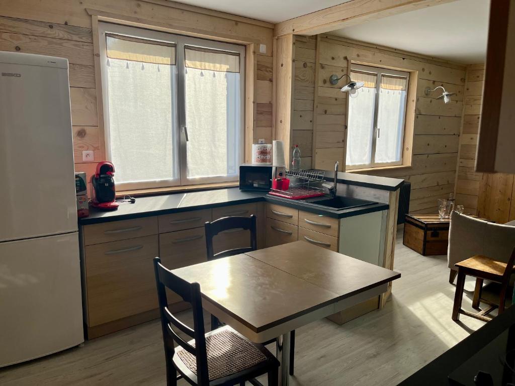 a kitchen with a table and a refrigerator at Appart Chez NONO in Patornay