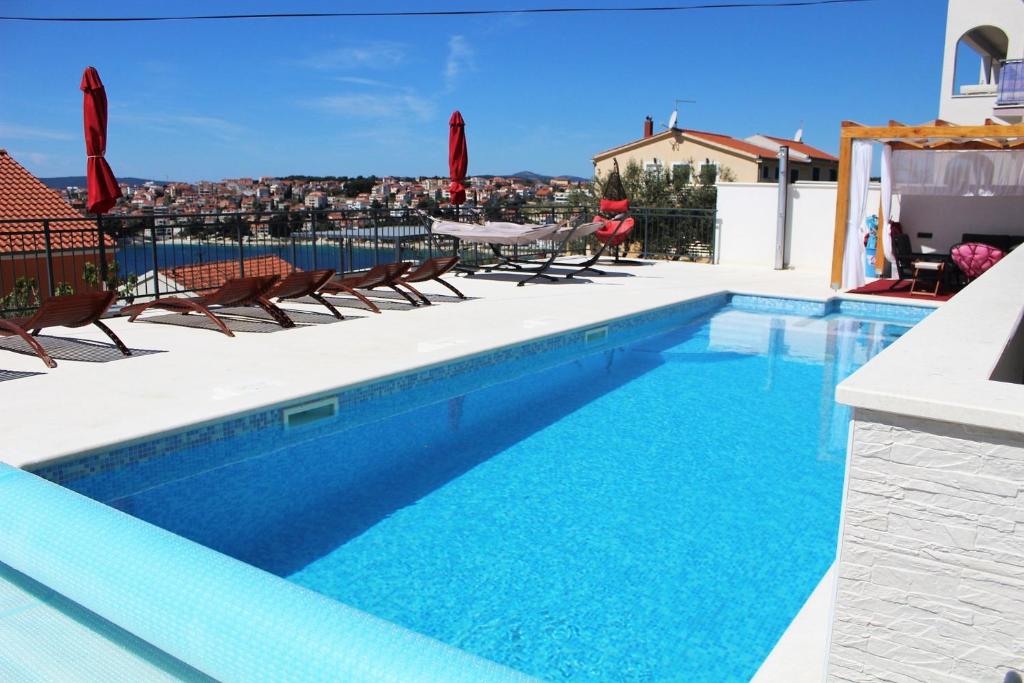 a swimming pool with chairs and a table on a building at Apartmani Zora in Trogir