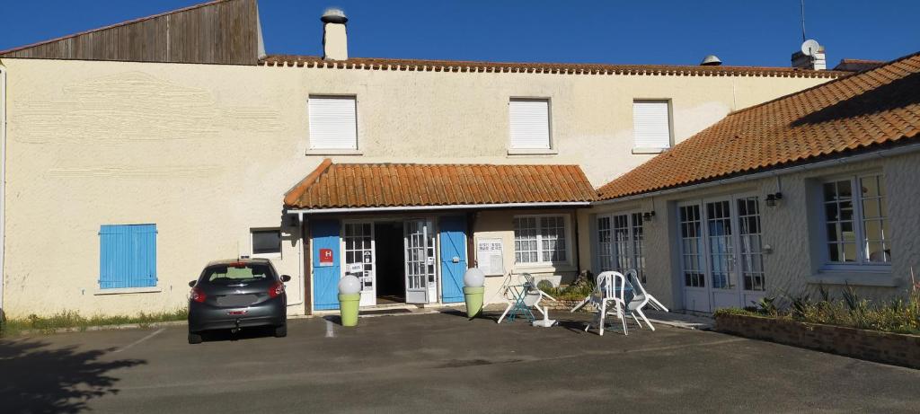 um carro estacionado num parque de estacionamento em frente a um edifício em Hotel La Chaumière em Saint-Jean-de-Monts