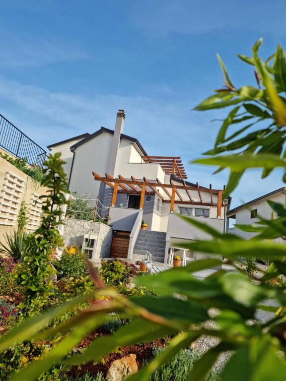 a large white house with some plants in the foreground at Apartman Luce in Krk