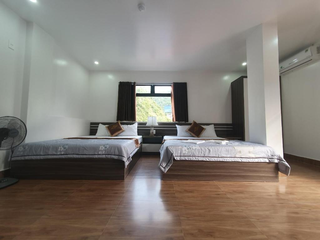 dwa łóżka w dużym pokoju z oknem w obiekcie Khách sạn Sông Chanh 3 Cát Bà w mieście Cát Bà