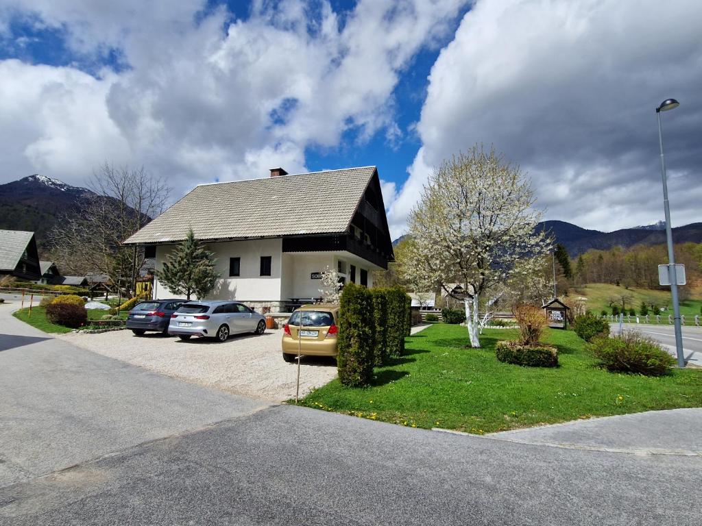 a house with cars parked in a parking lot at Sobe Ćuskić in Bohinj