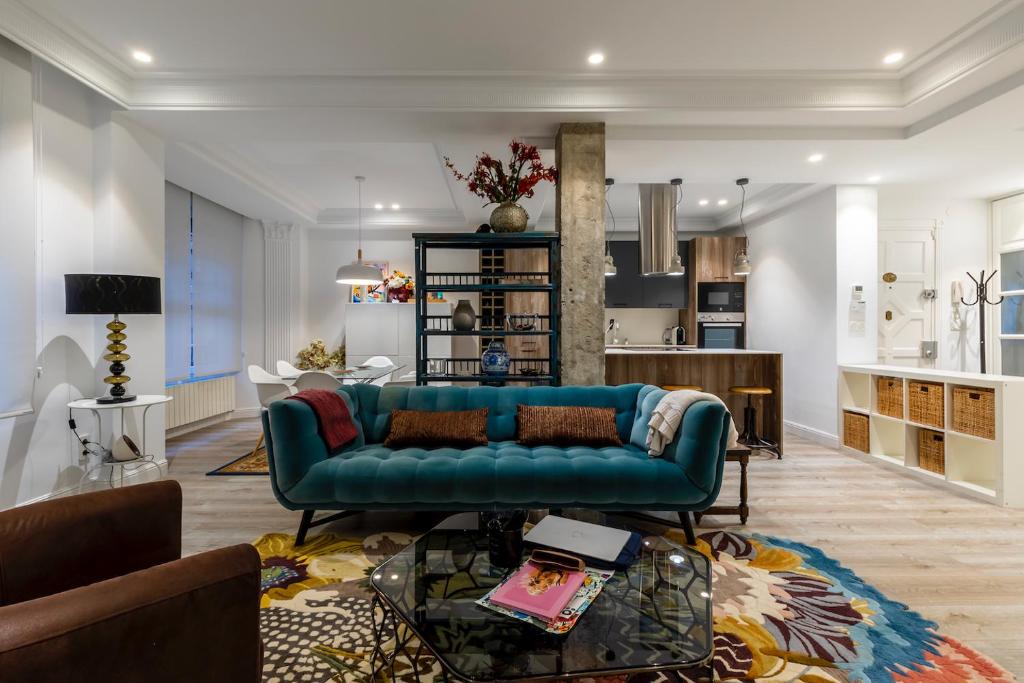 a living room with a blue couch and a kitchen at 110 M2 Central apartment in Abando Close To Guggenheim with parking in Bilbao