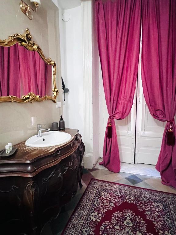 W łazience znajdują się różowe zasłony, umywalka i lustro. w obiekcie Sofia Katane Suites w Katanii