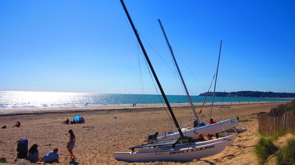 - un groupe de personnes sur une plage avec un voilier dans l'établissement Maison avec jardin à 80 m de la plage de Barneville-Carteret, à Saint-Jean-de-la-Rivière