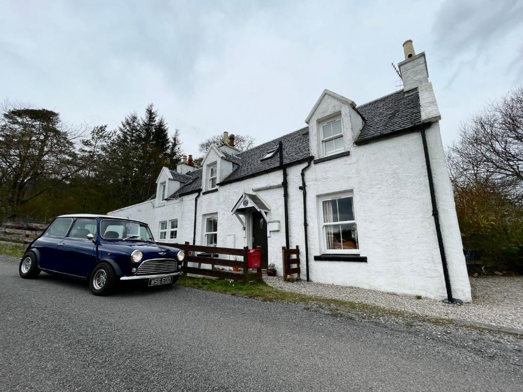 a blue car parked in front of a white house at 1 Keepers Cottage Skeabost Bridge Isle Of Skye in Skeabost