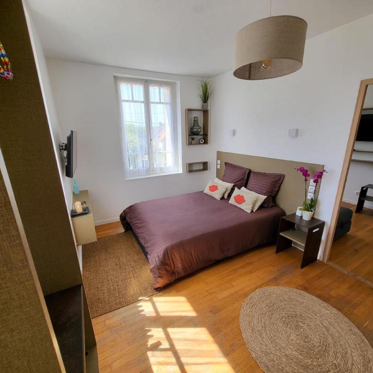 - une chambre avec un lit doté de draps violets et une fenêtre dans l'établissement Le Jardin du saumon, à Angé