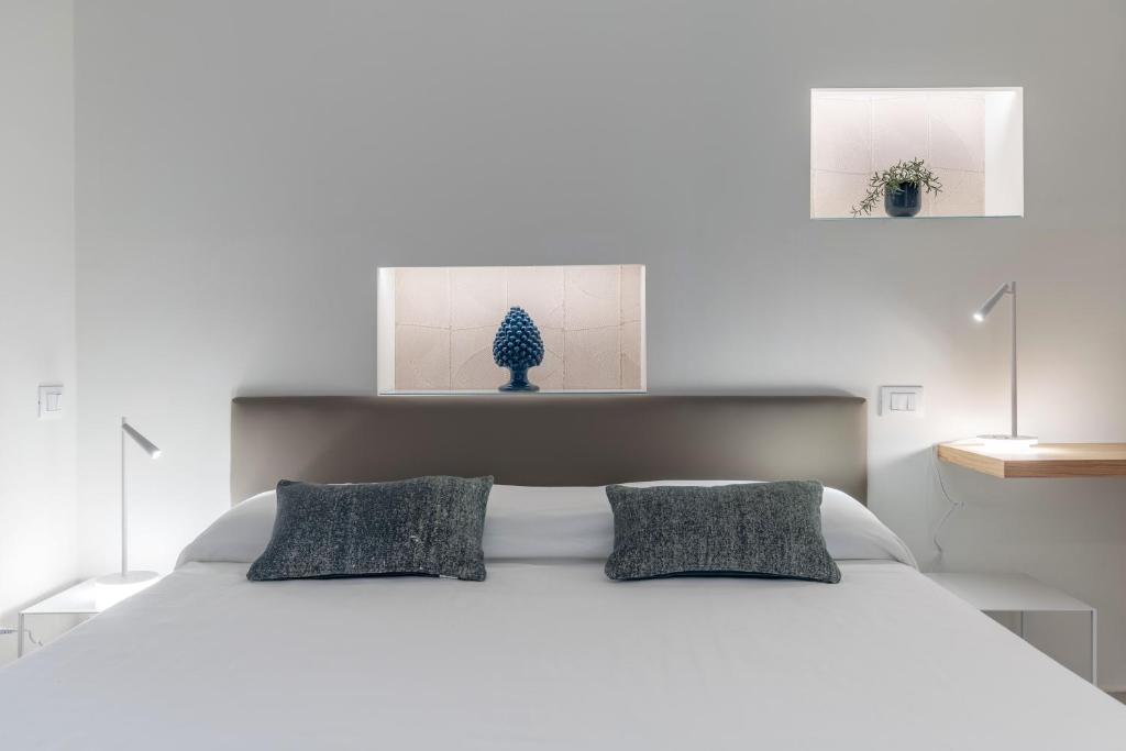 una camera bianca con un letto bianco con due cuscini di Taormina Town - Guesthouse Sicily a Taormina