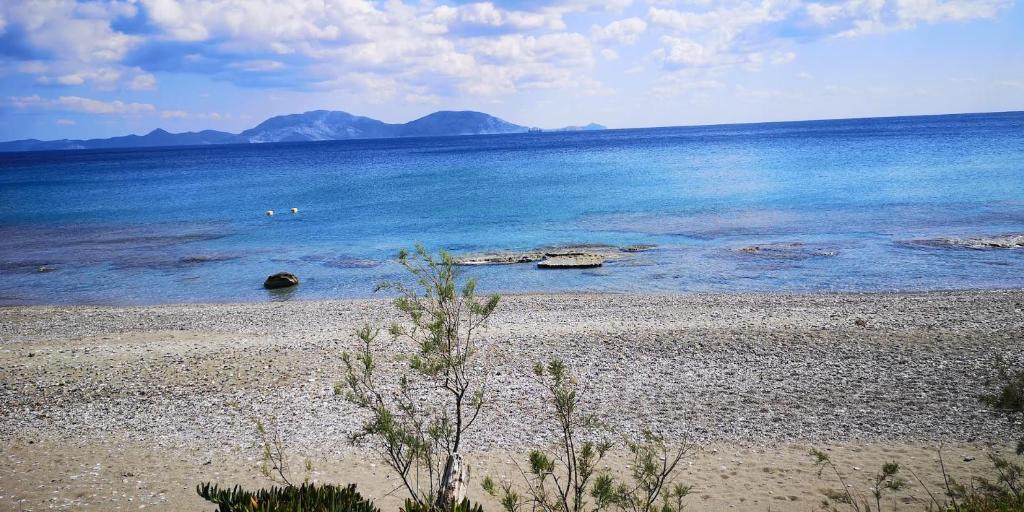 une plage avec de l'eau bleue et des montagnes en arrière-plan dans l'établissement Tiny Big House, à Fanari