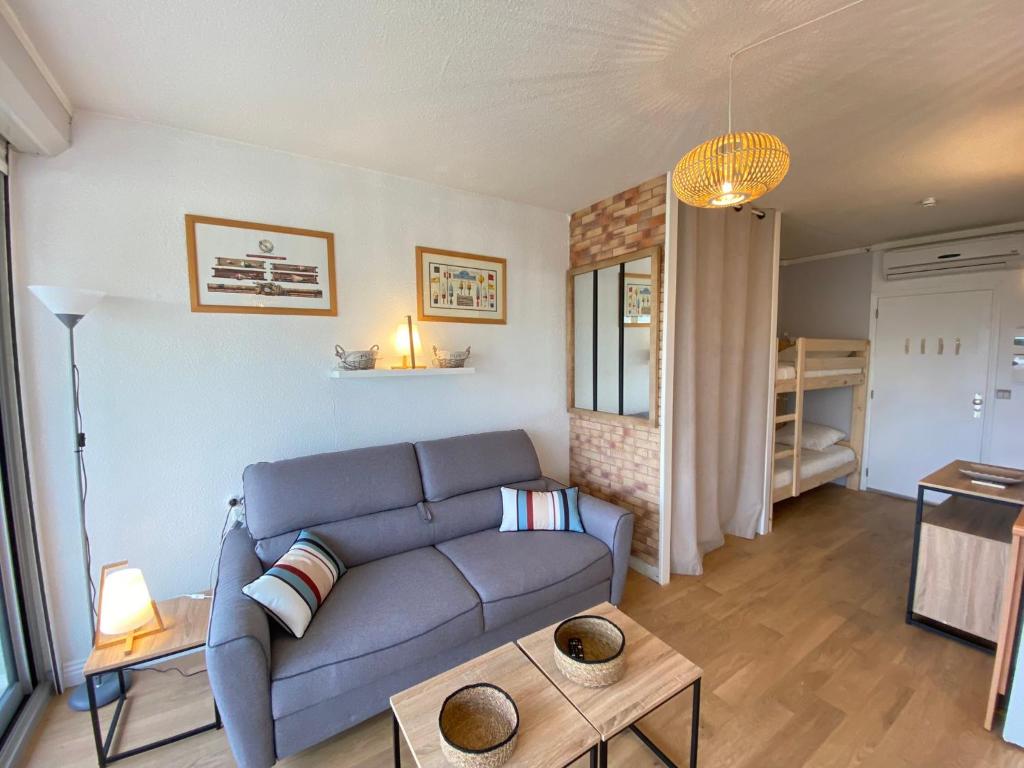 uma sala de estar com um sofá azul e uma mesa em 06N - Joli studio - piscine - tennis - clim - proche mer em Saint-Laurent-du-Var