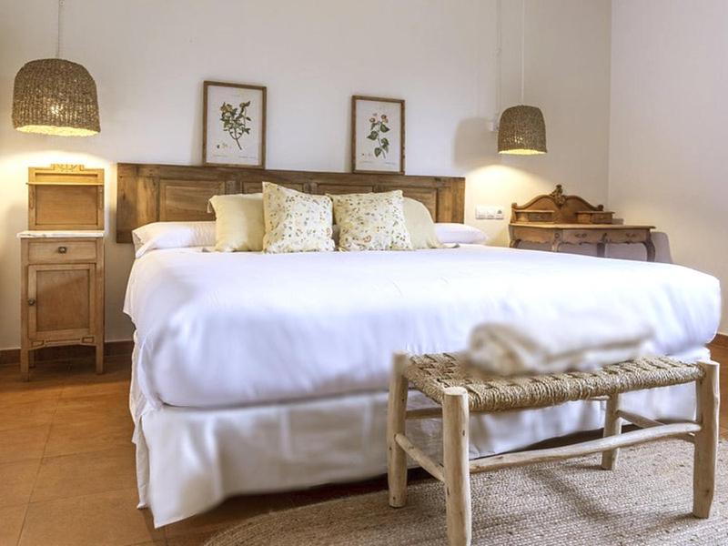 a bedroom with a large white bed and a chair at Apartamentos Rurales El Mirador de San Juan in Cangas de Onís
