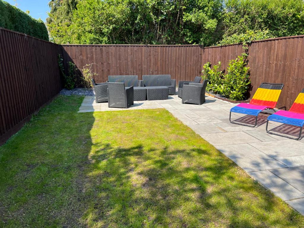 a patio with two chairs and a couch in a yard at Fantastic villa bournemouth - spa, parking, garden in Bournemouth