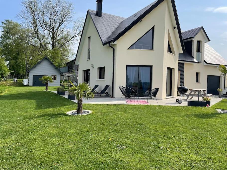 een groot wit huis met een grasveld bij Maison chaleureuse au calme in Roumare