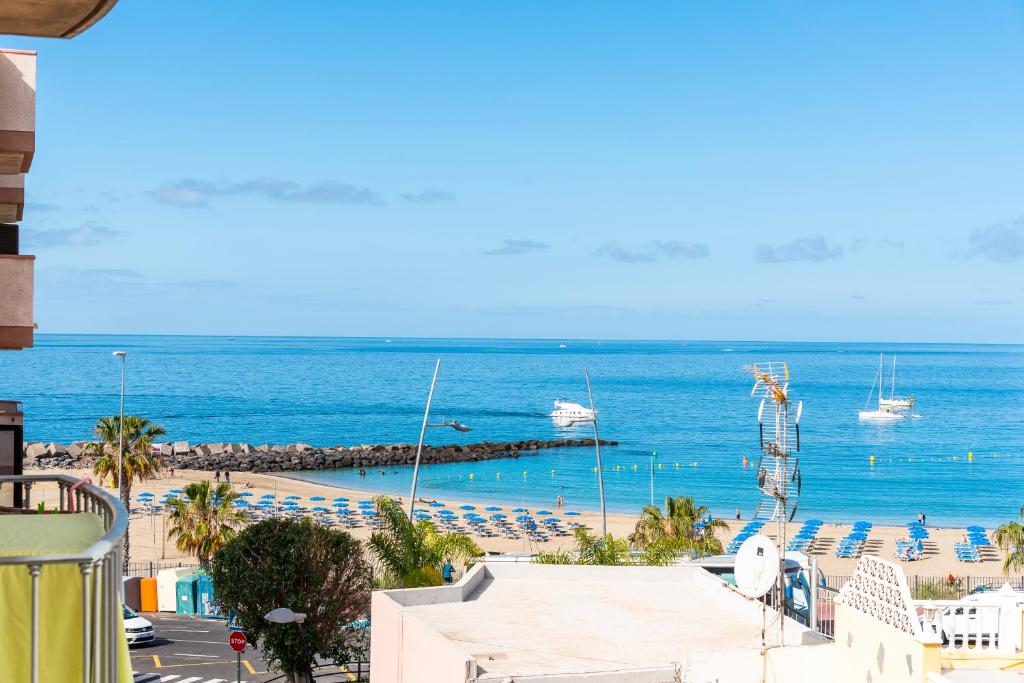 widok na plażę z krzesłami i łodziami w wodzie w obiekcie 17 LOS CRISTIANOS CENTRAL by the BEACH ,WiFi w Aronie