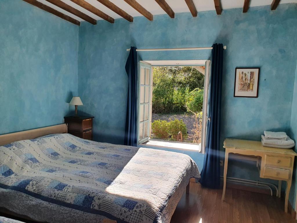 um quarto com paredes azuis, uma cama e uma janela em Ferme équestre & Chambres d'hôtes Gateau Stables proche Guédelon em Saint-Amand-en-Puisaye