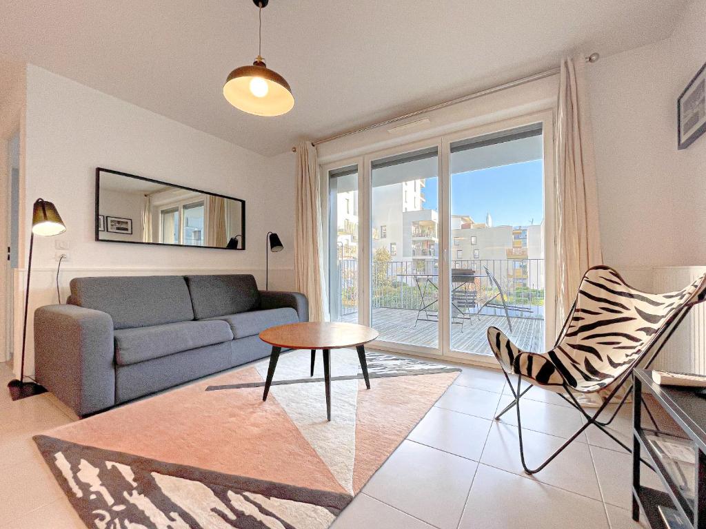 uma sala de estar com um sofá e uma mesa em Appartements avec parking - Cite du Vin em Bordeaux