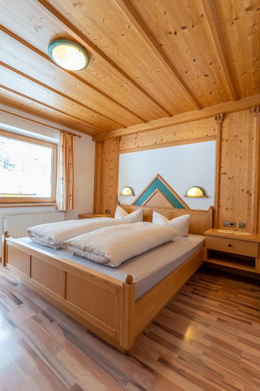 un letto grande in una stanza con soffitto in legno di Fernerblick Apartments a Tux