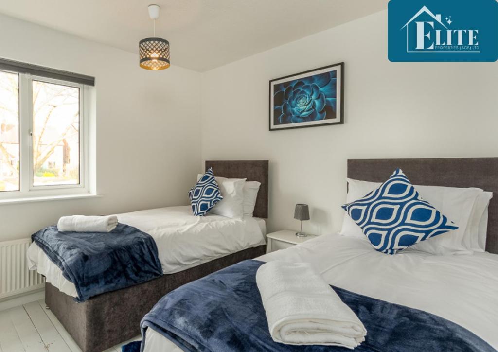 a bedroom with two beds with blue and white pillows at House with Garden & Private Driveway - Elite Properties in Leamington Spa