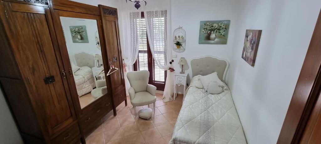 a bedroom with a bed and a chair and a mirror at Dolce shabby in Modica