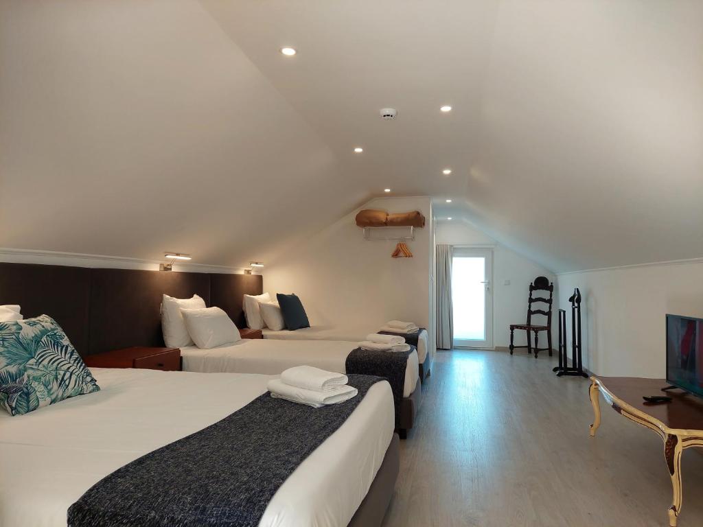 a hotel room with two beds and a television at Hall 92 Quartos com WC em moradia com piscina A-das-Lebres Loures in Loures