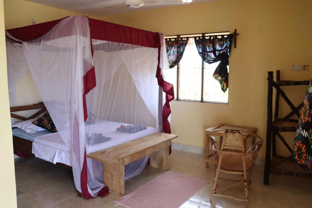 a bedroom with a canopy bed and a wooden table at Tipitipi house in Kizimkazi