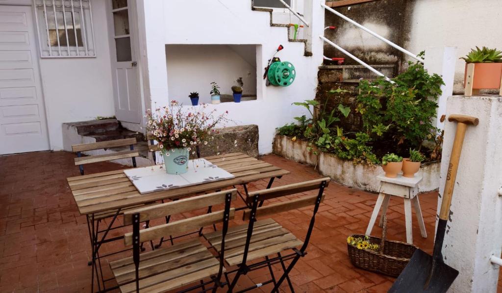 un patio con mesa de madera, sillas y plantas en Casco antiguo con patio y a 5 min de la playa, en Baiona