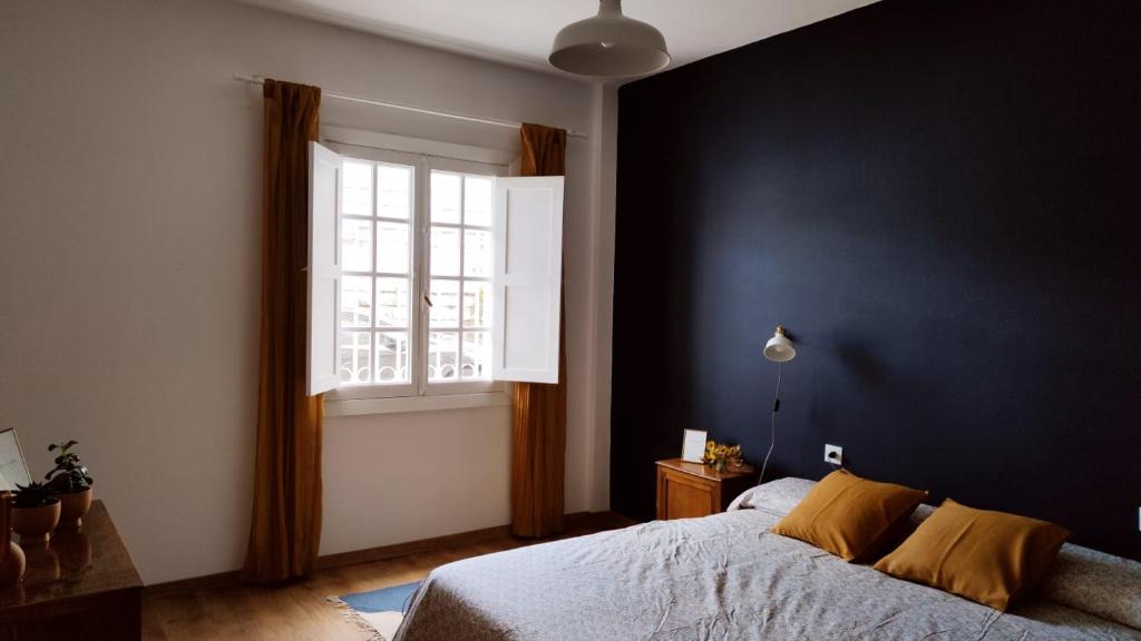 Un dormitorio con una cama grande y una ventana. en Casco antiguo con patio y a 5 min de la playa, en Baiona