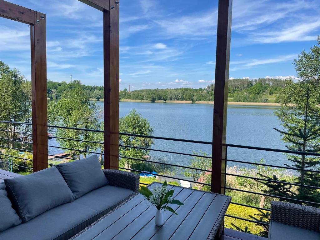 um alpendre com um sofá e vista para um rio em Wakacyjny Hartowiec - dom nad brzegiem jeziora em Grodziczno