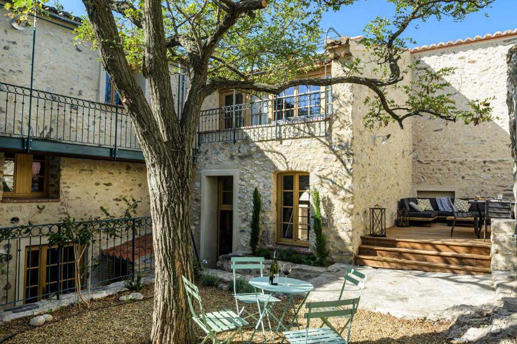 un patio frente a una casa con un árbol en LA MAISON DU CHATEAU en Bélesta