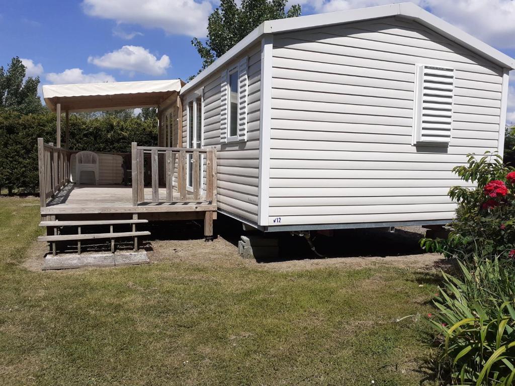 a white house with a porch and a bench at Mobil-Home/Bungalow in Le Perrier