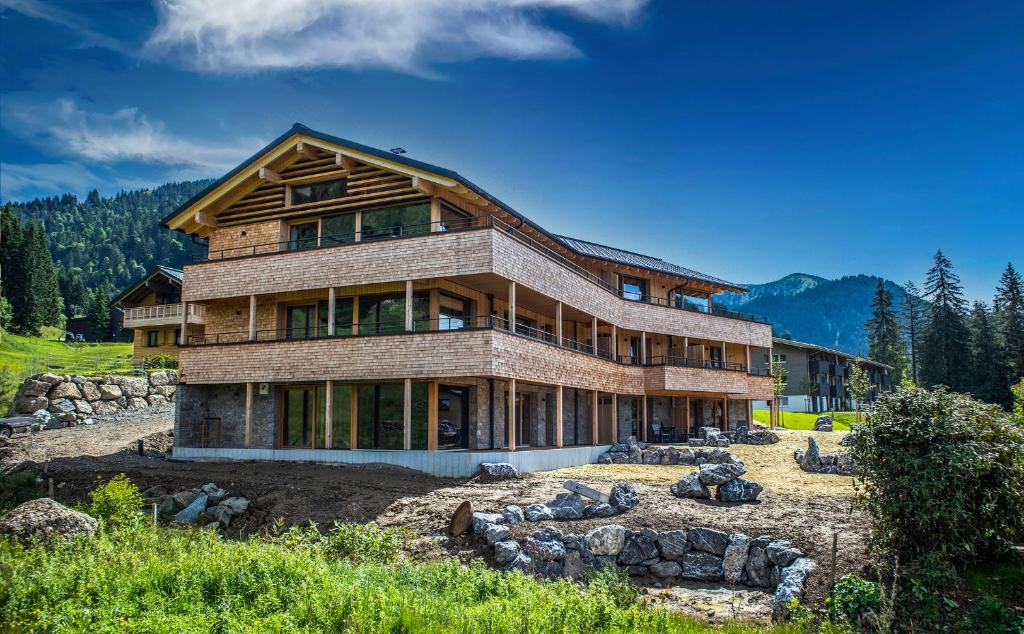 uma grande casa de madeira numa colina com montanhas em Gästehaus Oben am Berg em Balderschwang